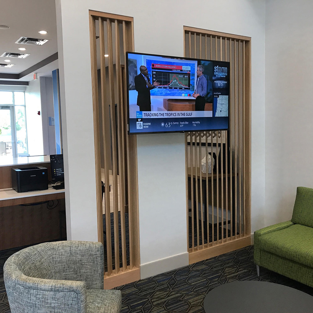 Custom woodwork vertical slats in a customer lounge area with a flat screen TV on the wall.