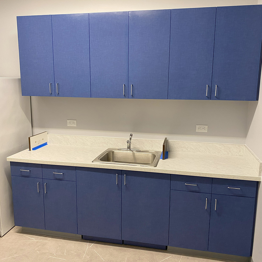 Sink and bright blue cabinets in an employee break room.