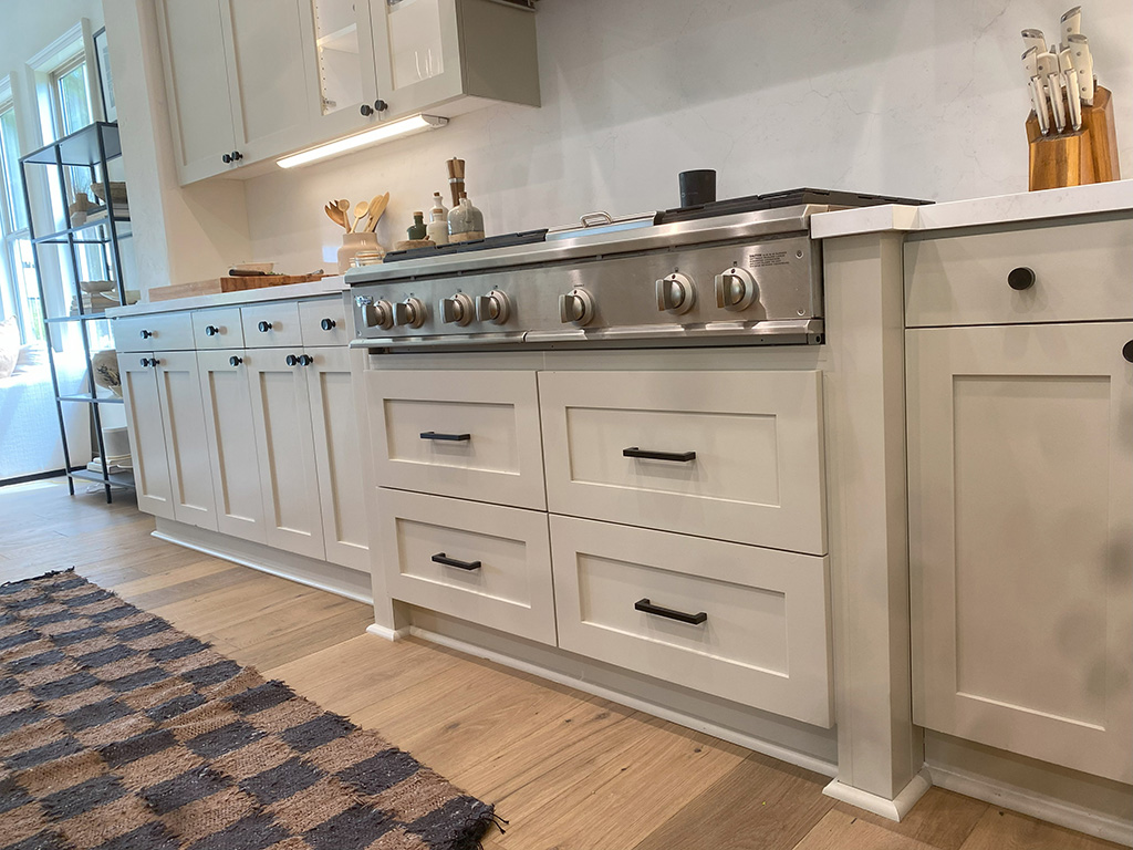 Low angle view of white kitchen cabinets and drawers with a stovetop in the center.