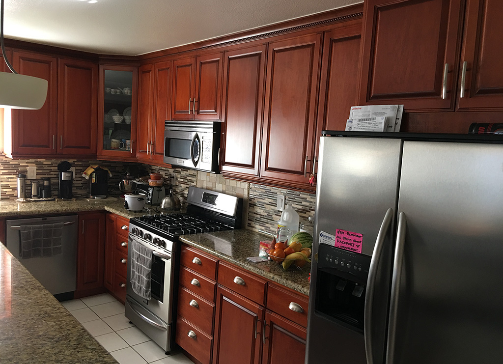 Remodeled kitchen with island, dark wood cabinets and drawers, side view.