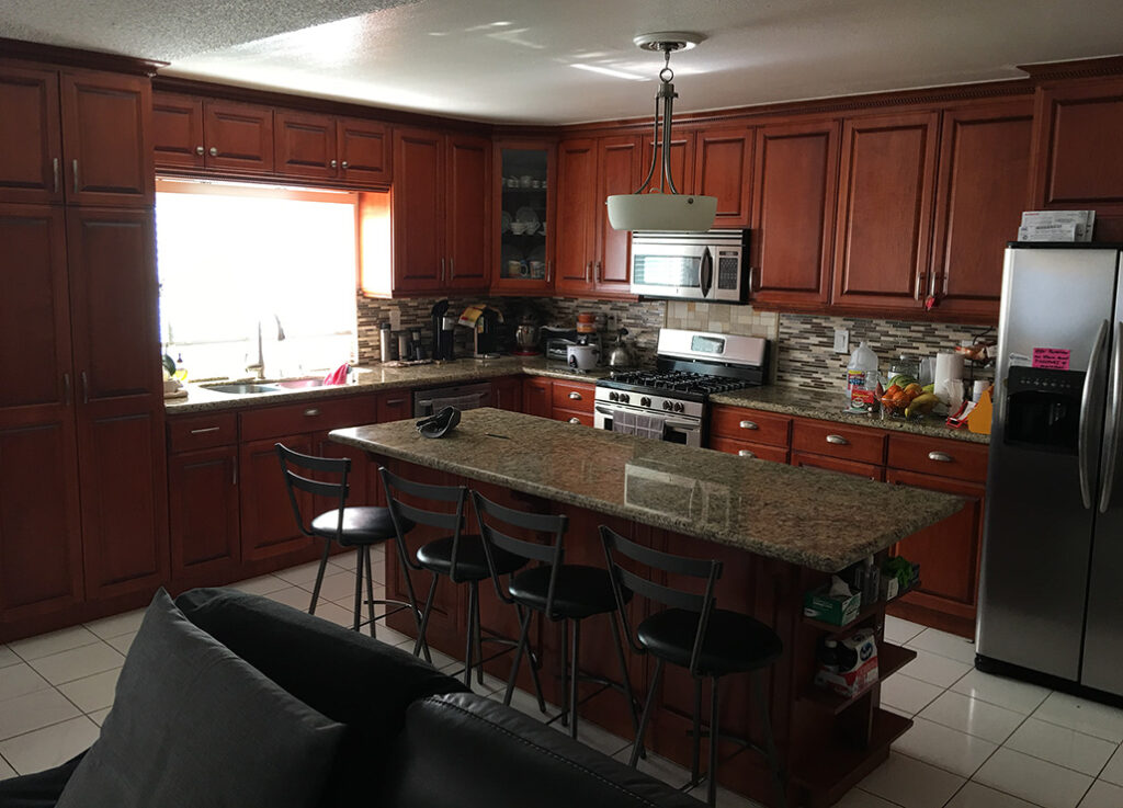 Remodeled kitchen with cabinets drawers and island in dark wood.