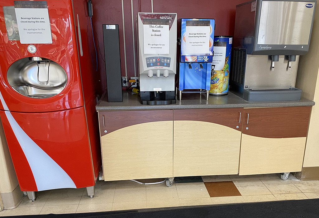 Custom wooden counter at a restaurant with soda machines on top and a Coke machine to the left side.